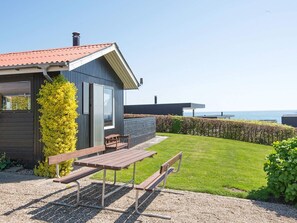 Un bâtiment moderne doté d’un patio, de bancs et offrant une vue sur la mer.