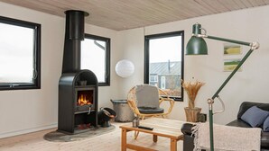 A cozy living room with a fireplace, a sofa, a chair, a coffee table, and a lamp. - 5 Person Holiday Home in Juelsminde-by Traum (Horsens)