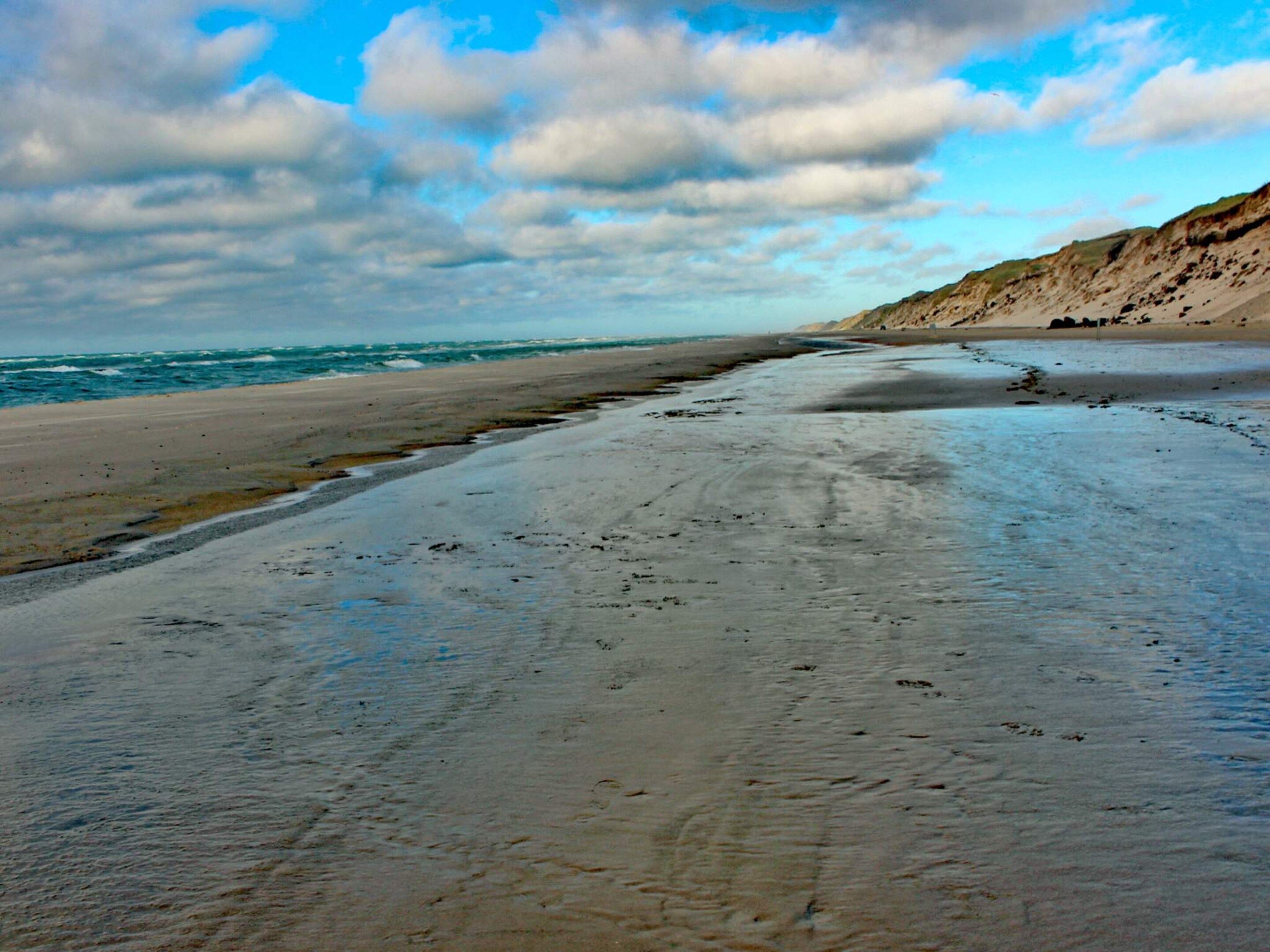 A beach with a sandy shore and a rocky cliff in the background.