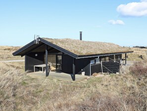 A modern building with a grass-covered roof, a wooden deck, and a staircase leading to the entrance. - 6 Person Holiday Home in Skagen (Skagen)