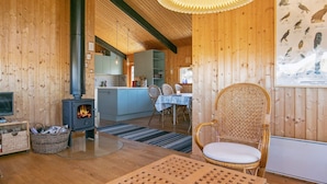 A cozy wooden interior with a fireplace, dining area, and a poster of birds. - 6 Person Holiday Home in Skagen (Skagen)