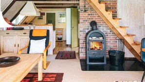 Ein gemütliches Interieur mit Kamin, einer Holztreppe und einem Essbereich.