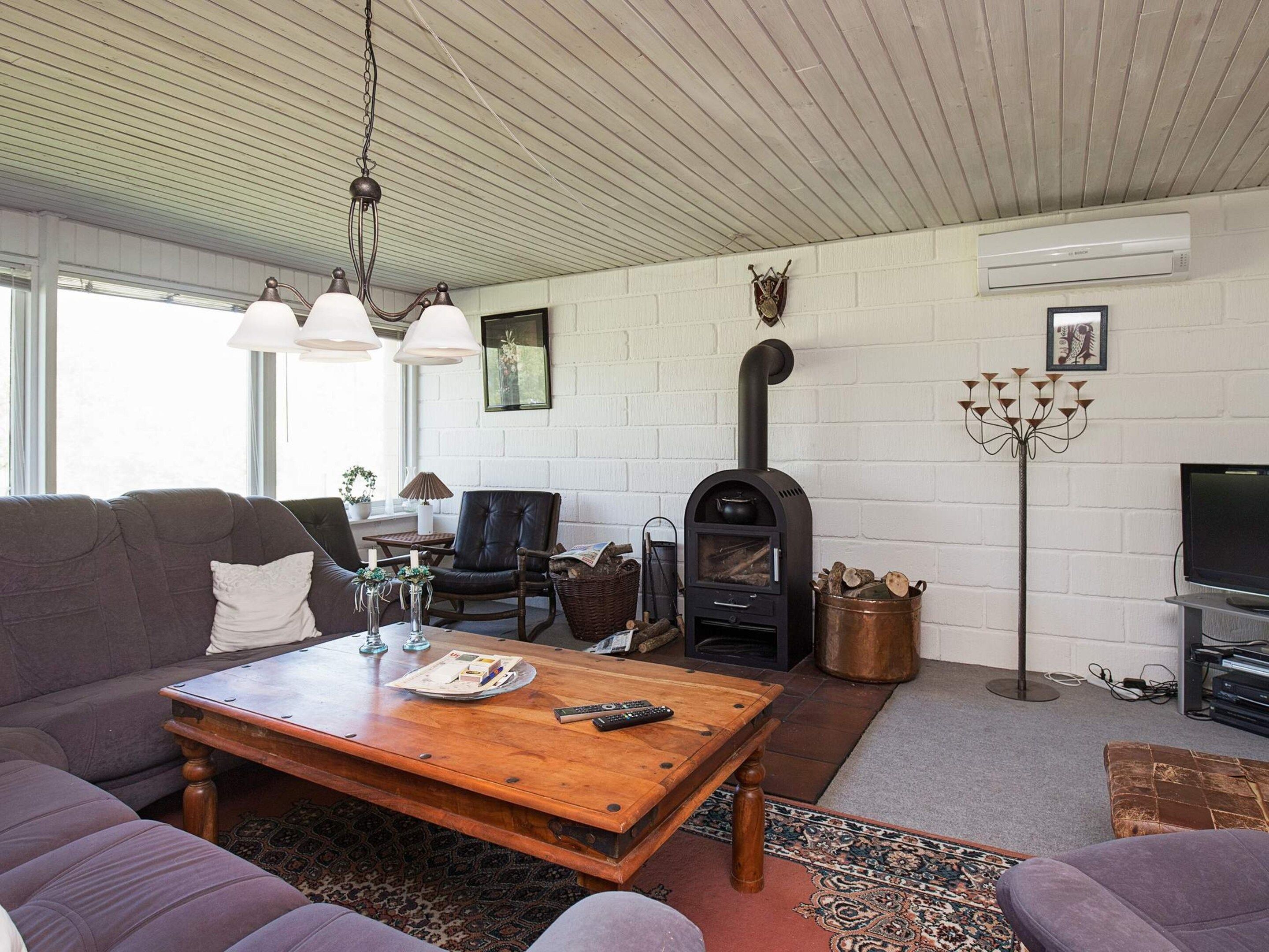 Una sala de estar con un sofá, una mesa de centro, una chimenea, un televisor y un aire acondicionado instalado en la pared.