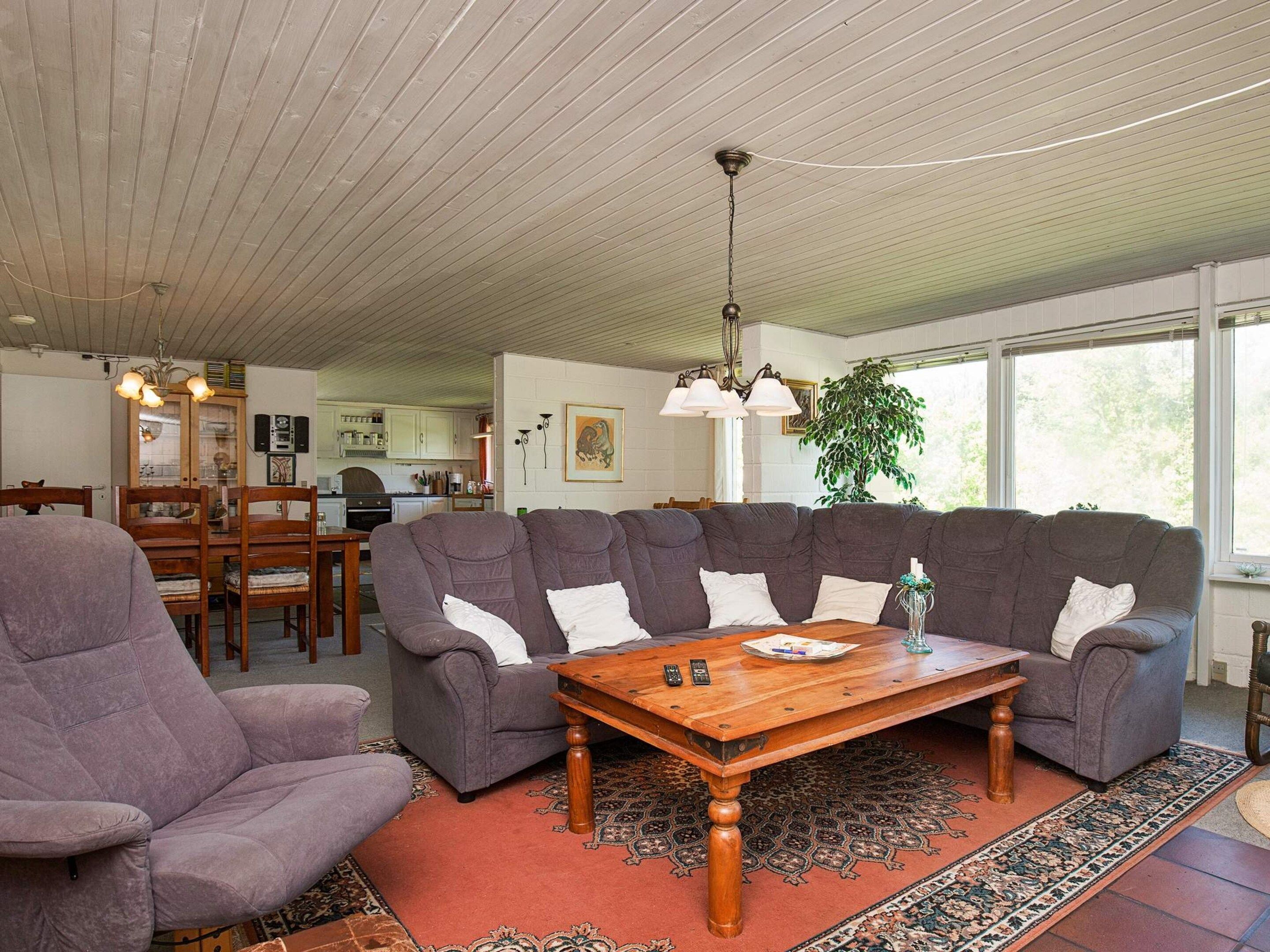 A living room with a sectional sofa, a wooden coffee table, and a patterned rug.