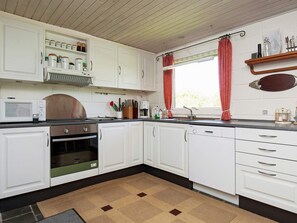 A kitchen with white cabinets, a microwave, an oven, and a sink. - 6 Person Holiday Home in Farso-by Traum (Farso)