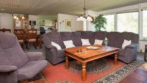 Una sala de estar con un sofá modular, una mesa de centro de madera y una alfombra estampada.