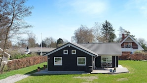 A black house with a tiled roof, a number '67' on the side, and a small patio area.