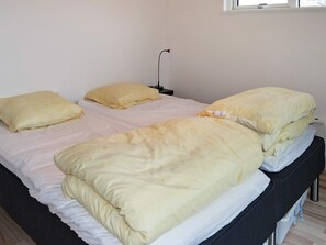 A single bed with a white mattress and a yellow blanket, a bedside table with a lamp, and a window with a view of the outside. - 10 Person Holiday Home in Hadsund-by Traum (Hadsund)