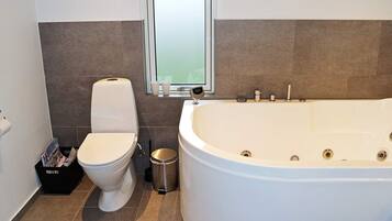 Une salle de bain avec des toilettes, une poubelle et une baignoire.