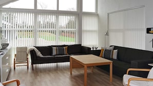 A modern living room with a sofa, two armchairs, a coffee table, and a dining table.