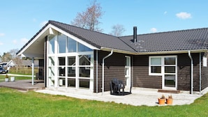 A modern house with a large glass window, a covered porch, and a chimney.