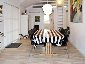 A dining area with a striped tablecloth, black chairs, a wooden table, and a hanging light fixture.
