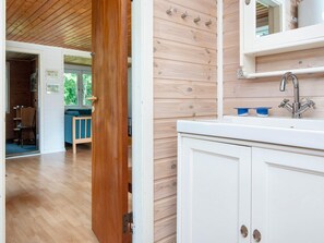 A modern kitchen with white cabinets, a stainless steel sink, and a wooden ceiling.