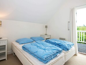 A bedroom with a bed, a nightstand, a lamp, and a view of the outdoors. - 8 Person Holiday Home in Gjern-by Traum (Gjern)