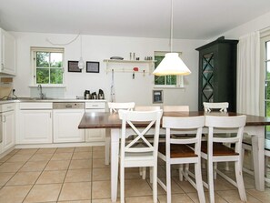 A kitchen with white cabinets, a wooden dining table, and four white chairs. - 8 Person Holiday Home in Gjern-by Traum (Gjern)