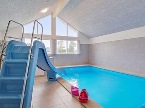 An indoor swimming pool with a blue slide, clear windows, and tiled walls. - 5 Star Holiday Home in Grenaa (Grenaa)