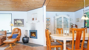 Ein gemütliches Wohnzimmer mit Kamin, einem Essbereich mit Holzkästen und einer weißen Ziegelwand.