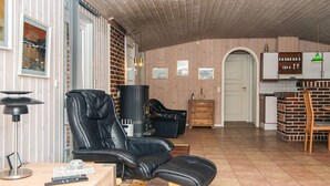 Una sala de estar moderna con un sillón reclinable de cuero, una chimenea, un comedor y una cocina con armarios de madera.