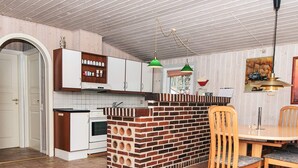 Una cocina con isla de ladrillo, armarios blancos y comedor con sillas de madera.