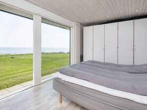 A bedroom with a large bed, a wardrobe, and a view of the sea. - 6 Person Holiday Home in Odder (Odder)