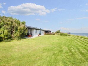 A modern house with a well-maintained lawn and a view of the sea.