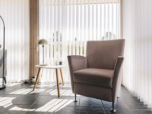 A room with a large window, a chair, a table with a lamp, and a floor with patterned tiles. - 5 Star Holiday Home in Lokken (Lokken)