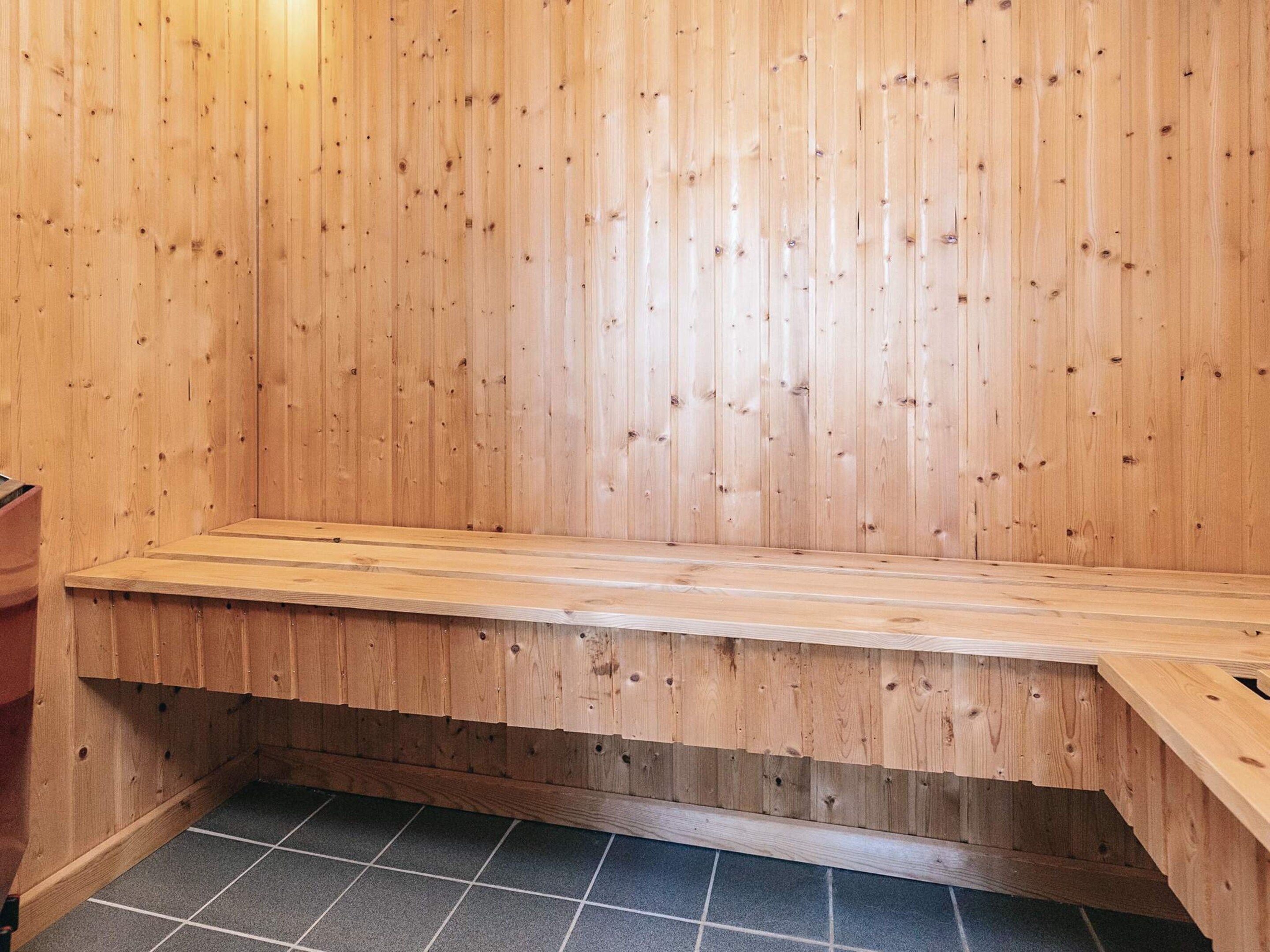 A wooden bench in a room with a tiled floor.