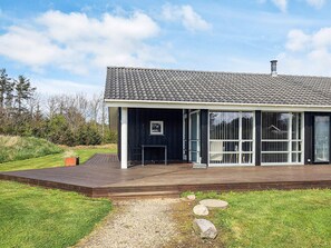 A modern house with a dark exterior, large windows, and a wooden deck. - 5 Star Holiday Home in Lokken (Lokken)