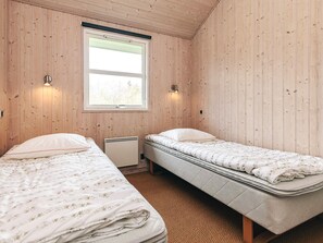 A room with two beds, wooden walls, a window, and wall-mounted lights. - 5 Star Holiday Home in Lokken (Lokken)
