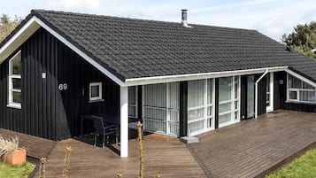 A modern black house with a sloped roof, a deck, and a number '69' on the side.
