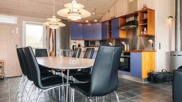 A modern kitchen with a dining area, featuring a round table with chairs, pendant lighting, and built-in cabinets.