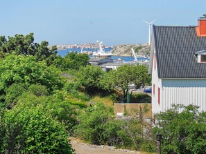 Uma vila costeira com vista para o mar, uma turbina eólica e um edifício com telhado inclinado.