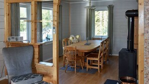 A cozy cabin interior with a wooden dining table, chairs, a gray armchair, a small sofa, a fireplace, and a radio. - 8 Person Holiday Home in Uggdal (Tysnes)