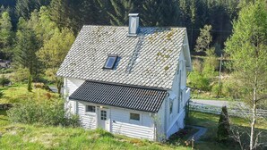 A white wooden house with a sloped roof, a chimney, and a small window. - 8 Person Holiday Home in Uggdal (Tysnes)