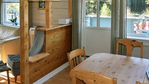 A wooden dining area with a table and chairs, a bench, and a window with a view of trees and a building. - 8 Person Holiday Home in Uggdal (Tysnes)