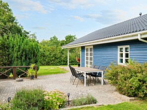 A blue house with a covered patio, a table with chairs, and a hanging chair. - 9 Person Holiday Home in Jaegerspris-by Traum (Jægerspris)