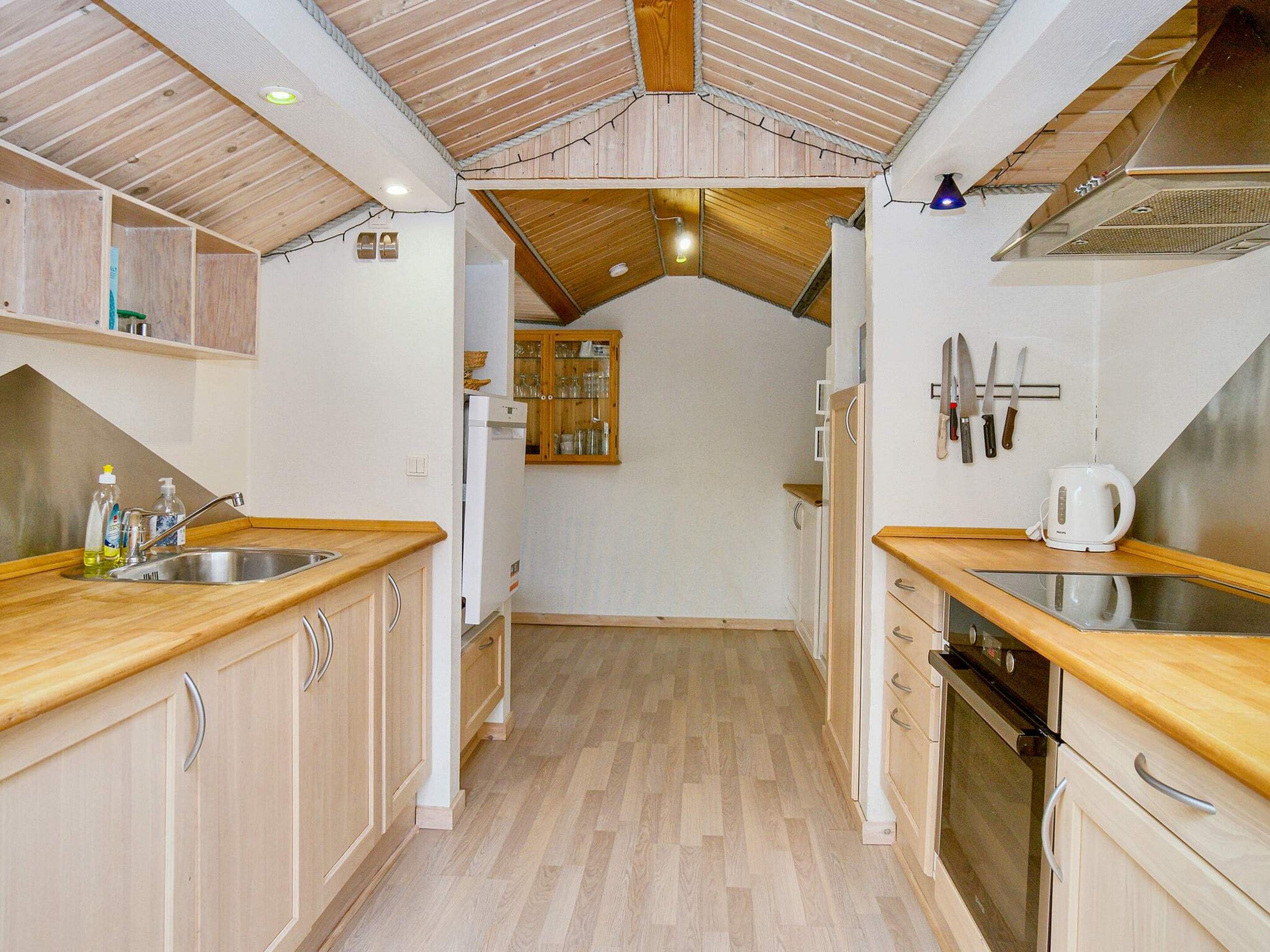 Una cocina con armarios de madera, un lavamanos de acero inoxidable y un horno empotrado.