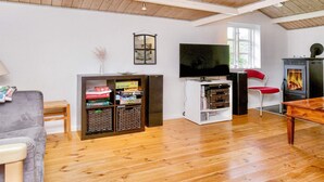 A cozy living room with a wooden ceiling, a television, a bookshelf, and a fireplace. - 9 Person Holiday Home in Jaegerspris-by Traum (Jægerspris)