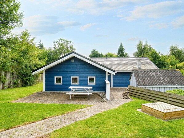 A blue building with a white porch and a wooden bench.
