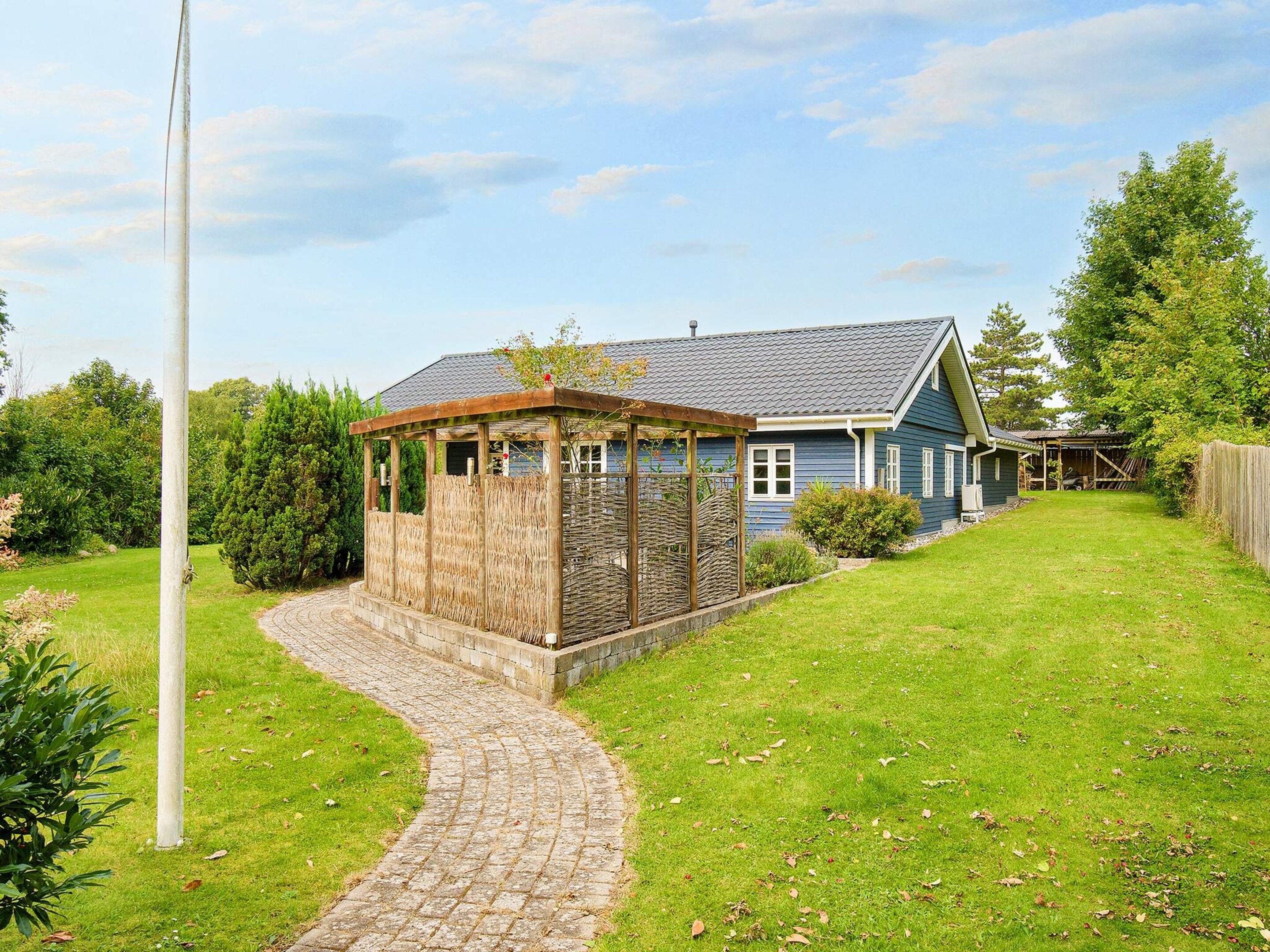 A house with a covered outdoor area, a paved pathway, and a grassy yard.