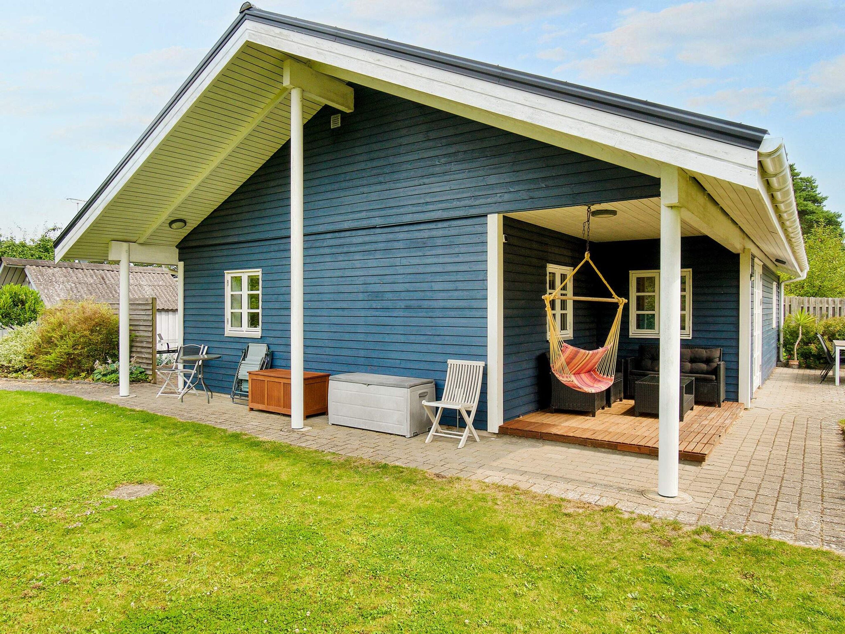 A house with a covered porch, outdoor furniture, and a hanging chair.