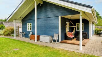 A house with a covered porch, outdoor furniture, and a hanging chair.