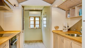 A narrow kitchen with wooden cabinets, a built-in oven, and a coffee maker. - 9 Person Holiday Home in Jaegerspris-by Traum (Jægerspris)