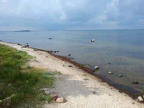 A coastal path with a sandy beach, scattered rocks, and a calm sea. - 9 Person Holiday Home in Jaegerspris-by Traum (Jægerspris)