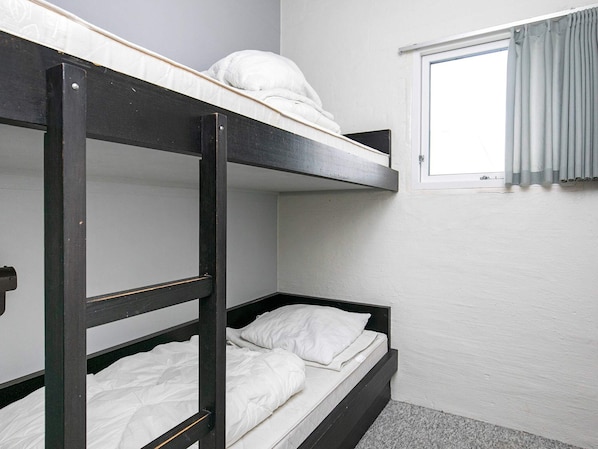 A bunk bed room with a window and curtains.