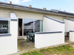 Il s’agit d’un bâtiment d’un seul étage doté d’un patio comprenant une table et des chaises, une porte-fenêtre coulissante et un petit espace extérieur aménagé pour s’asseoir.