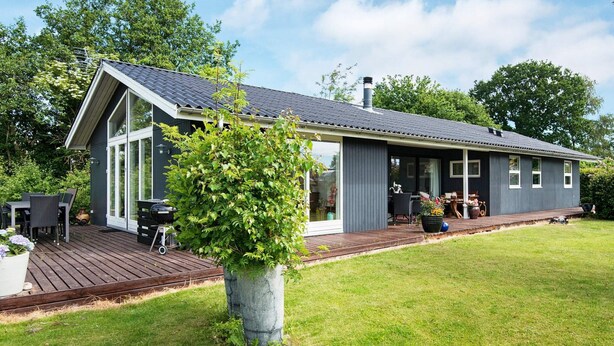 Uma casa moderna com um deck, uma janela grande e um jardim.