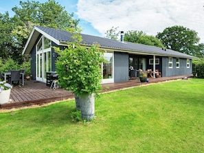 A modern house with a deck, a large window, and a well-maintained lawn. - 4 Star Holiday Home in Odder (Odder)