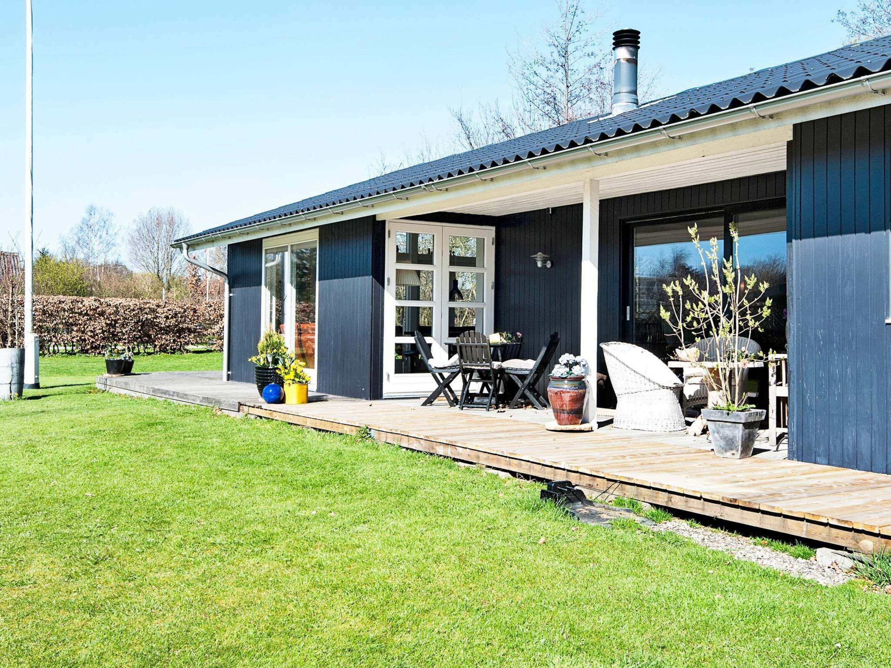 Et moderne hus med en overdækket veranda, et spiseområde med udendørs møbler og en have.