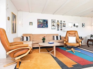 A living room with a sofa, two leather chairs, a coffee table, and a colorful rug. - 4 Star Holiday Home in Odder (Odder)